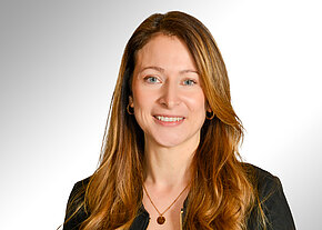 Stefanie Wernecke Porträtfoto einer lächelnden Frau mit langen, hellbraunen Haaren. Sie trägt ein dunkles Oberteil, eine Halskette und kleine Creolen. Heller, neutraler Hintergrund und ein freundlicher, professioneller Ausdruck.