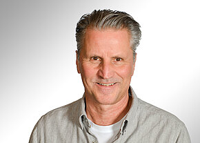 Markus Czesla Porträt eines lächelnden Mannes mittleren Alters mit grauen, zurückgekämmten Haaren. Er trägt ein helles Hemd über einem weißen T‑Shirt. Neutraler Hintergrund. Freundlicher Gesichtsausdruck, Blick in die Kamera.