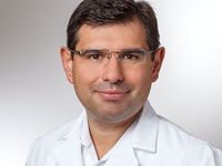 Dr. Roman Koshedub ist Leitender Oberarzt der Klinik für Akutrheumatologie und klinische Immunoligie an der Klinikum Bayreuth GmbH und Facharzt für innere Medizin und Rheumatologie. Ein Mann mittleren Alters mit kurzen, dunklen Haaren und Brille trägt einen weißen Arztkittel. Er lächelt freundlich in die Kamera. Der Hintergrund ist neutral und hell.